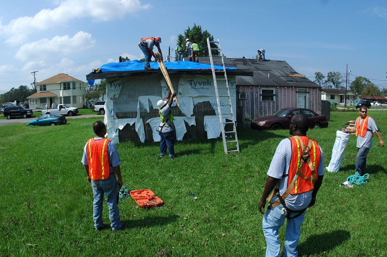 Tri-County inspector photographing hail dents in vinyl siding with a tablet after a storm