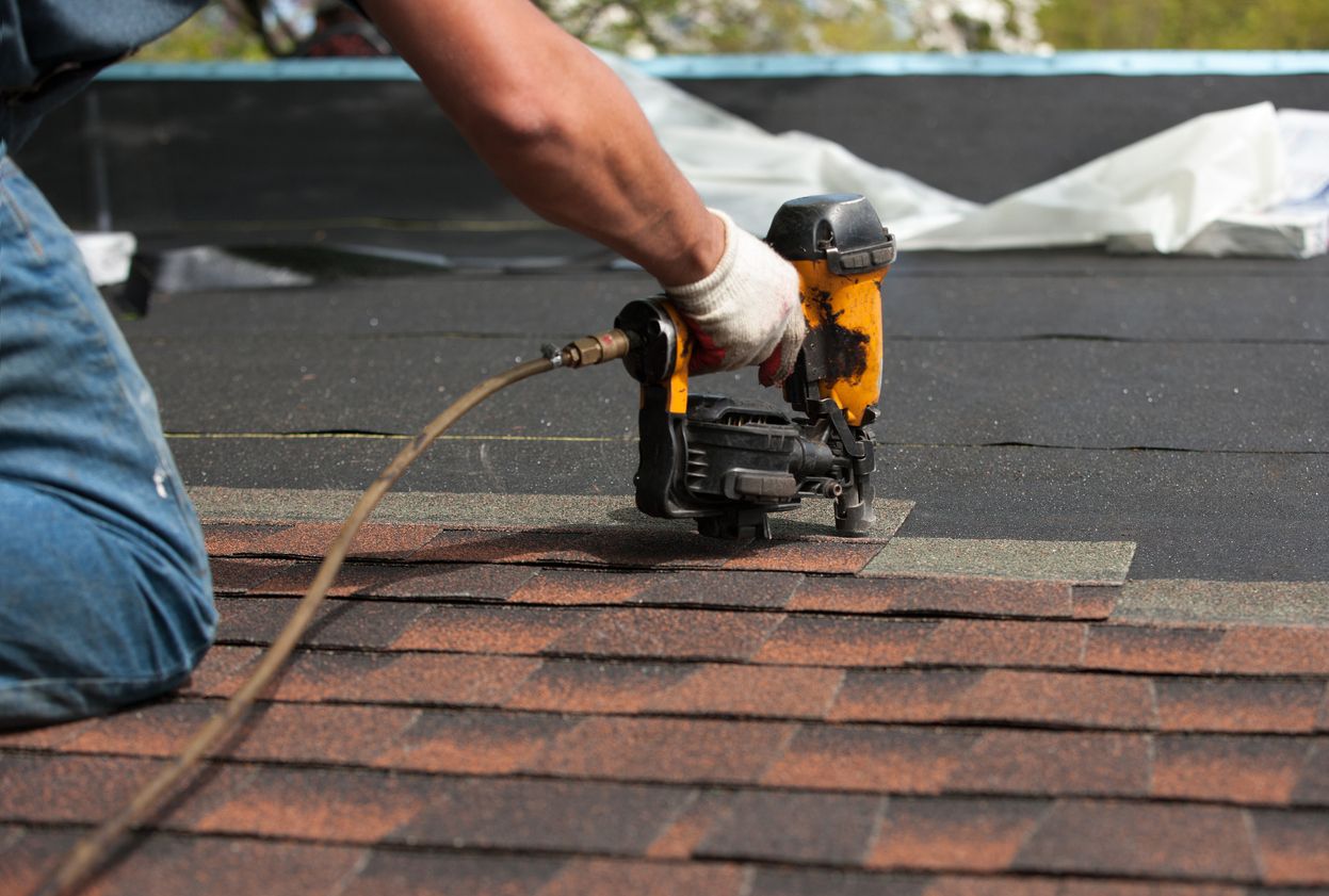 Roofer nailing architectural shingles on a residential roof